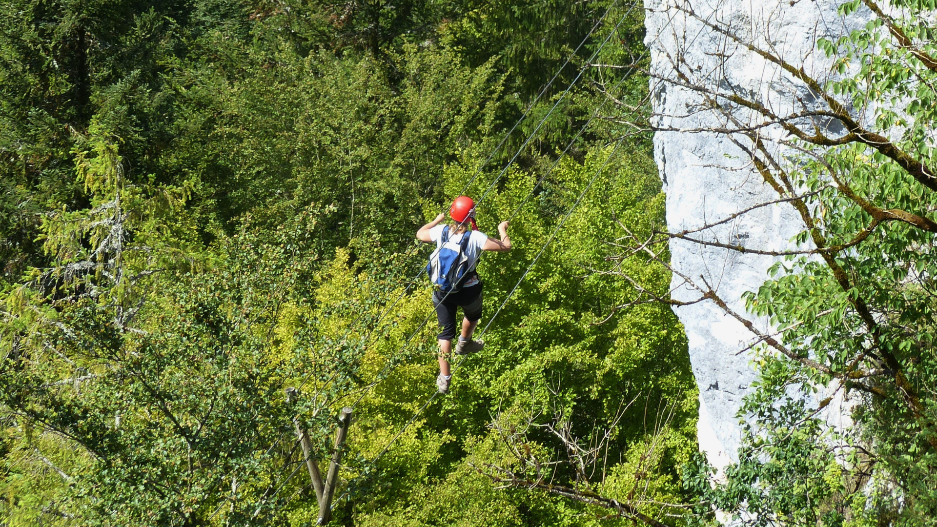 Vue sur les Échelles de la Mort de Charquemont, 1 personne sur des fils d'acier qui traverse entre deux roches.