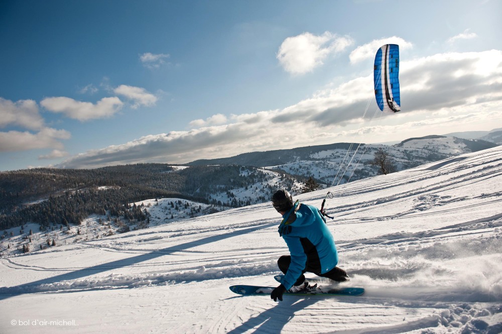 un skieur sur des pentes enneigées avec une aile de kyte.