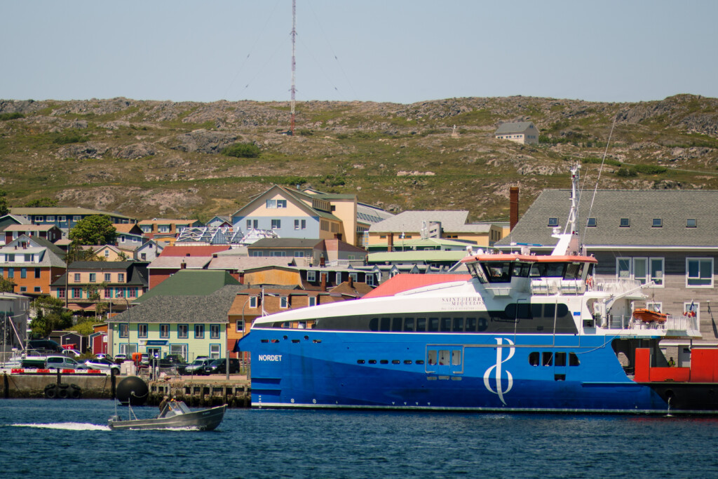 Le port de Saint-Pierre et ses maisons colorées, sous le soleil, ciel bleu, mer bleue.